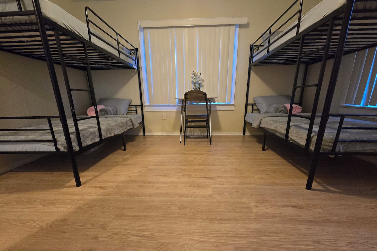 A room with two bunk beds, a small table, and a chair.