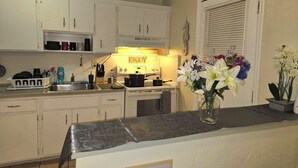 A kitchen with white cabinets, a stove, and a sink. There is a vase with flowers on the counter.