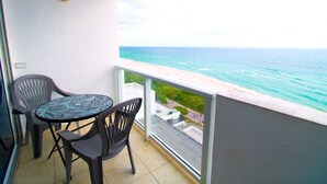 Ein Balkon mit Blick auf den Ozean, einem Tisch und zwei Stühlen.
