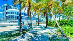 Ein Hotel direkt am Strand mit modernem Design, Palmen und einem Sandweg.