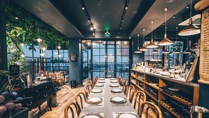 A restaurant with a long table set for dining, wooden chairs, hanging pendant lights, and a view through large windows. - sees the sea and sea view boutique B&B (Shenzhen)
