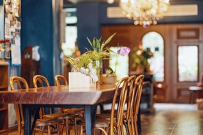 A wooden dining table with chairs, a vase with flowers, and a chandelier. - sees the sea and sea view boutique B&B (Shenzhen)