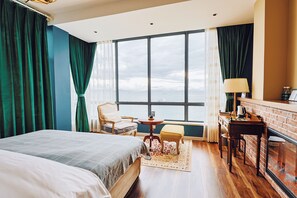 A hotel room with a large window, a bed, a chair, a small table, and a fireplace. - sees the sea and sea view boutique B&B (Shenzhen)