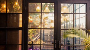 A room with a large window divided into multiple panes, each containing hanging light bulbs with plants inside. - sees the sea and sea view boutique B&B (Shenzhen)