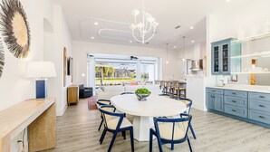 Une cuisine moderne dotée d’un grand îlot central, d’un coin repas avec une table ronde et d’une vue sur l’extérieur.