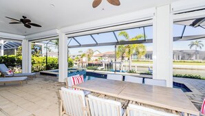 Un vaste espace extérieur doté d’une piscine, de chaises longues et d’une table en bois.