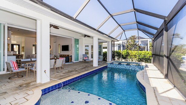 Une piscine intérieure dotée d’un toit en verre, un espace patio aménagé avec des sièges et une vue sur le paysage environnant.