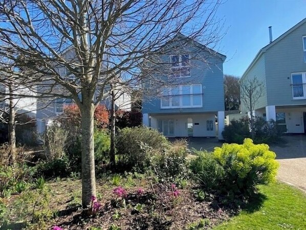 A residential area with two-story houses, a tree, and a well-maintained garden.