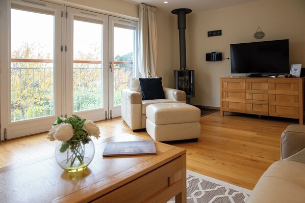 Una sala de estar moderna con un sofá, una mesa de centro de madera con un florero, un televisor y una chimenea.