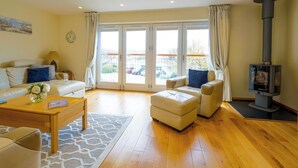 A spacious living room with a sofa, ottoman, and a fireplace.