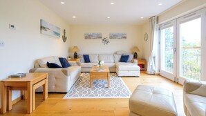 A spacious living room with a sofa set, a coffee table, and a wooden side table.