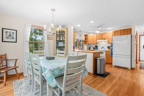 A cozy kitchen with wooden cabinets, a white refrigerator, and a dining area with a table set for four.