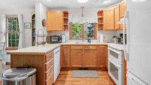 A kitchen with wooden cabinets, a microwave, a sink, and a refrigerator. - Woods Edge: Walk to Red River Beach, Pet Friendly (Harwich Port)