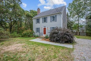 A two-story house with a red door and a chimney.
