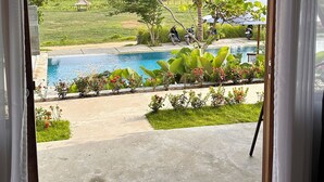 A view from inside a room to a pool area with a mountain in the background. - Maya Ocean Resort (Kuta)
