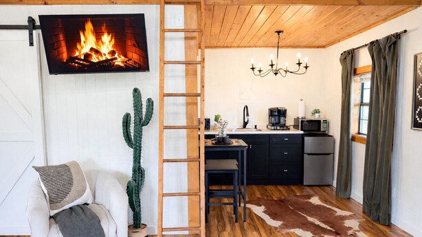 A cozy room with a fireplace, a dining area, and a kitchen. - The Cabin in Tracy City (Tracy City)