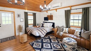 A spacious bedroom with a large bed, a leather sofa, a patterned rug, and a chandelier. - The Cabin in Tracy City (Tracy City)