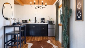 A compact kitchen with a wooden ceiling, a chandelier, a refrigerator, a coffee maker, and a cactus plant. - The Cabin in Tracy City (Tracy City)