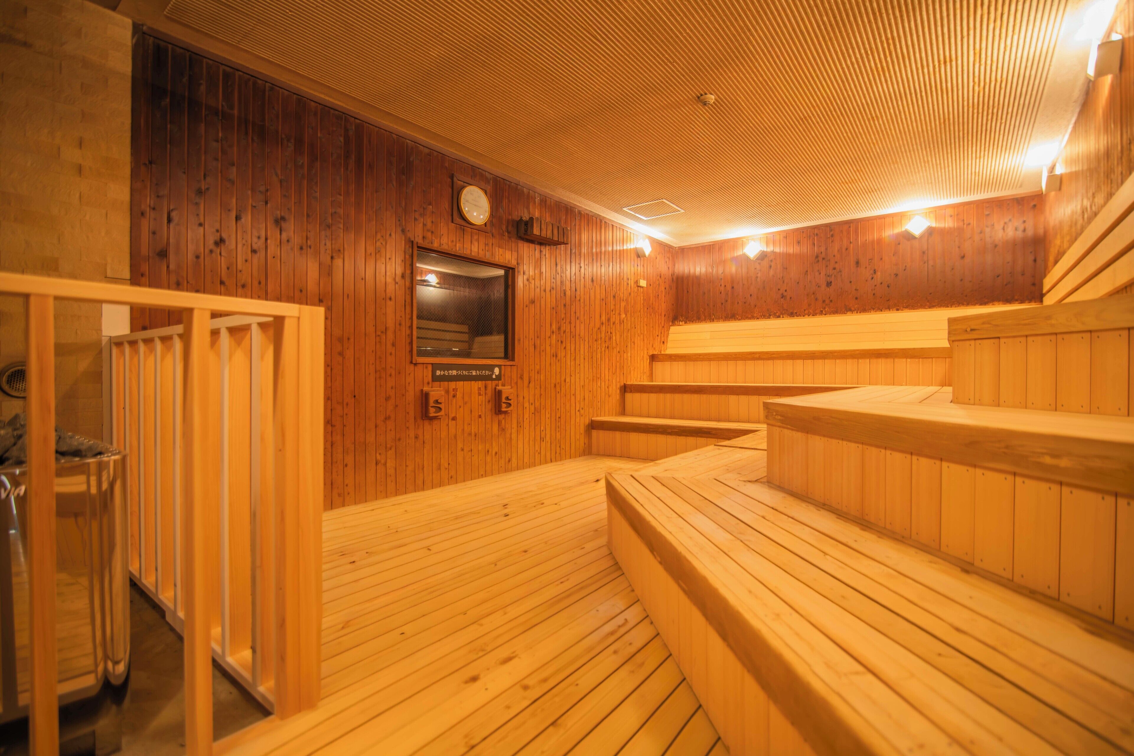 A wooden sauna with benches and a bench seat, a clock, and a mirror on the wall.