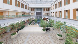 Un vaste atrium doté d’un haut plafond, de plusieurs niveaux et d’un espace central ouvert aménagé avec des sièges et de la verdure.