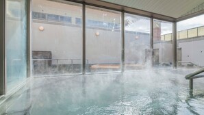 Une piscine intérieure à l’eau claire, dotée d’une paroi en verre et d’une rambarde en métal.