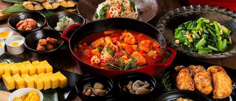 A variety of dishes including a red pot of stew, bowls of rice, and several side dishes.