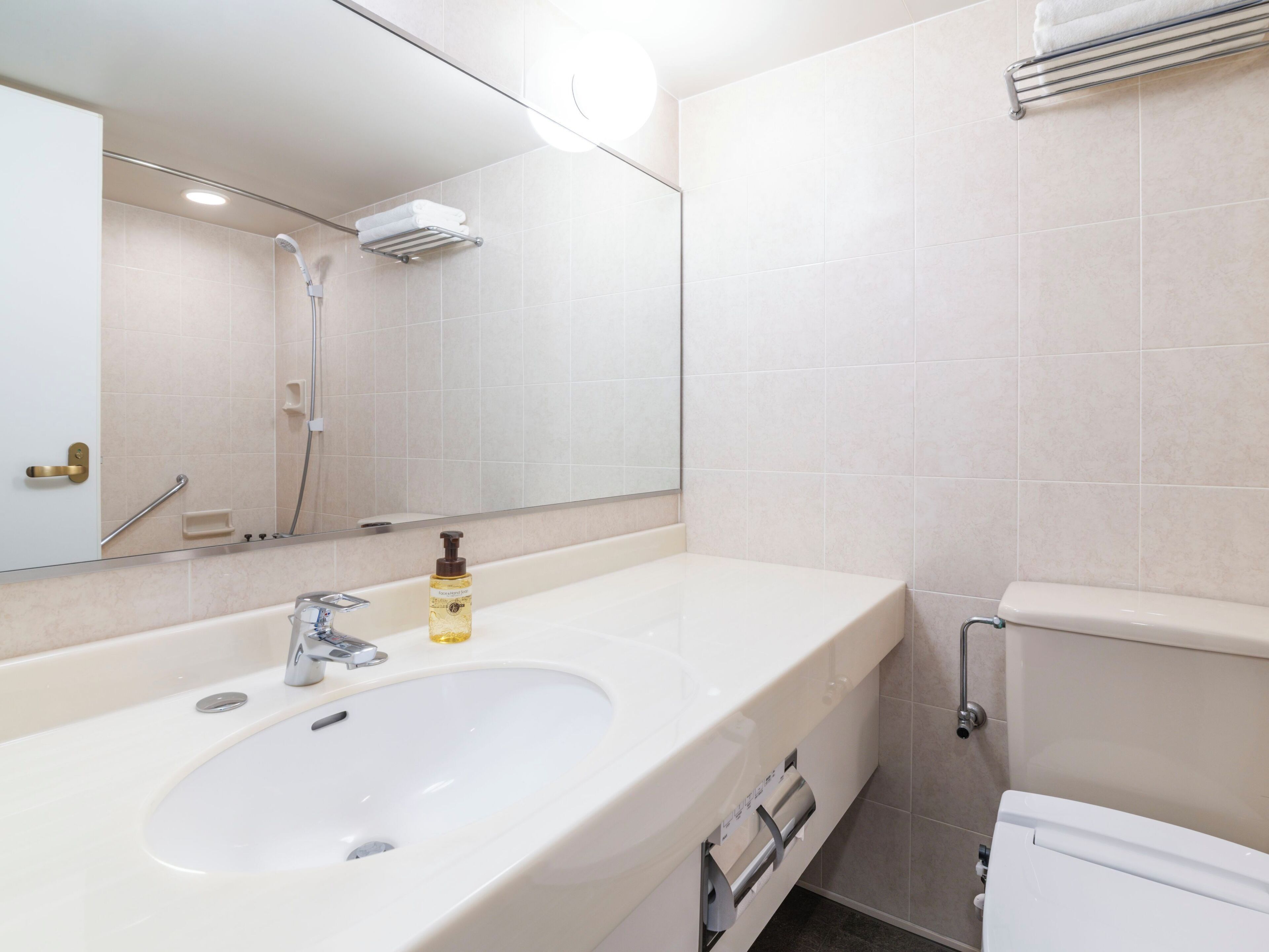 Un baño moderno con un lavabo grande, un espejo, una ducha y un inodoro.