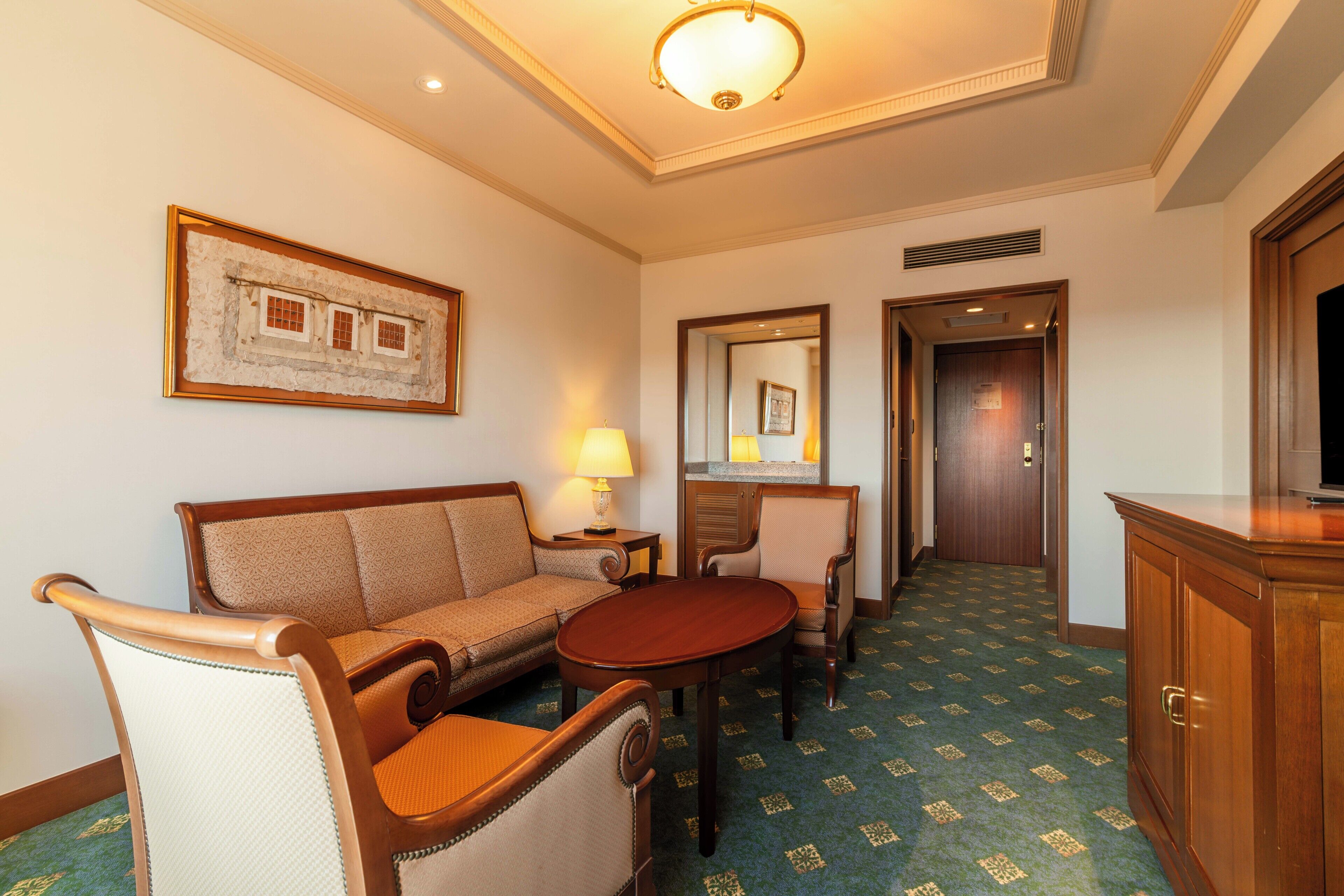 Una habitación de hotel con sofá, sillón, mesa y televisor.