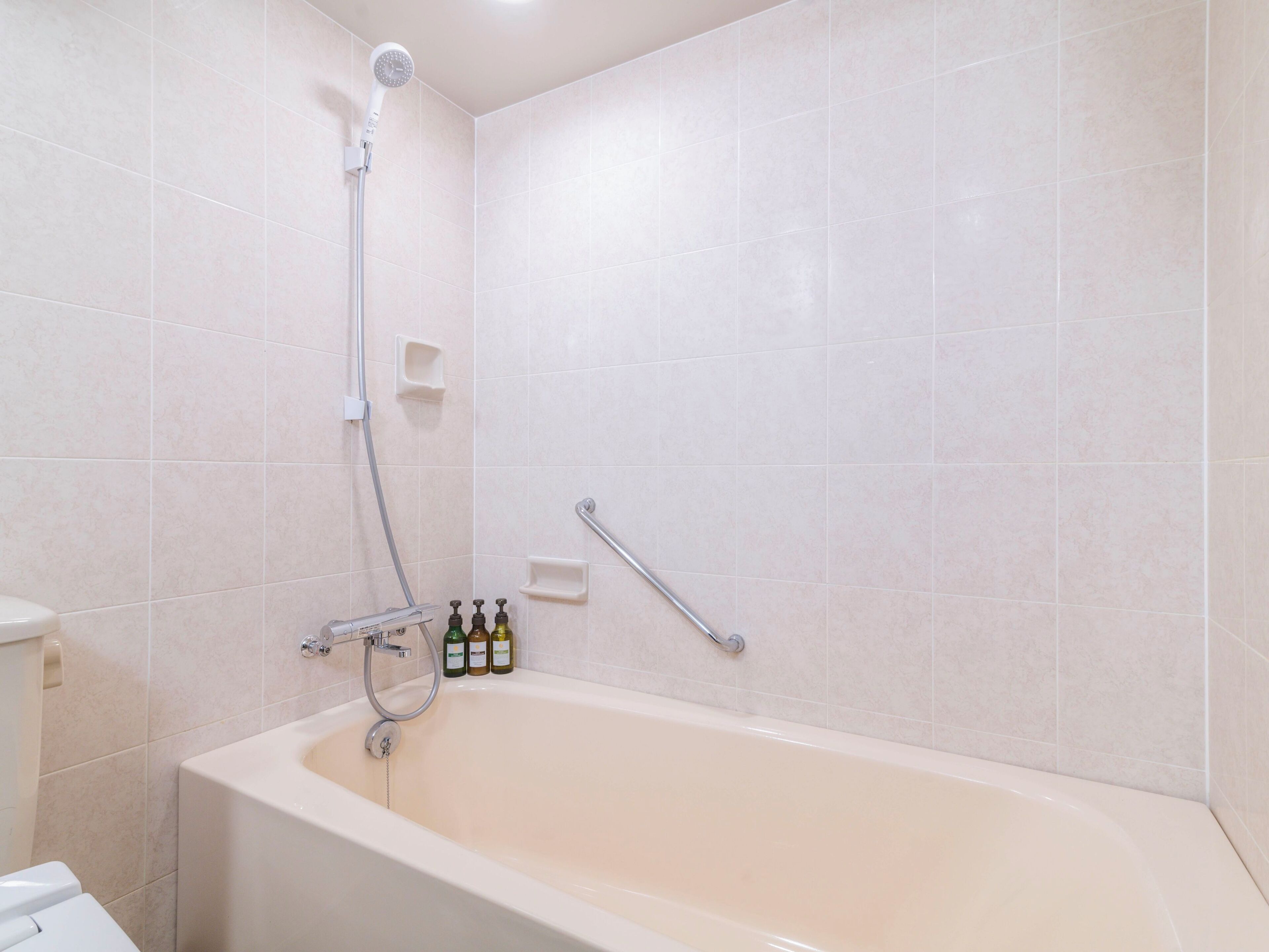 A modern bathroom with a bathtub, a showerhead, and a handrail.