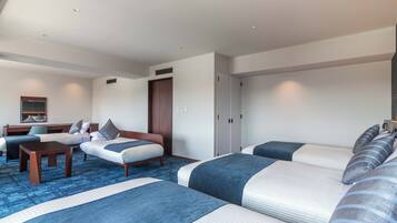 A hotel room with two beds, a desk, and a chair. There is a wardrobe and a mirror on the wall.