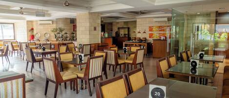 A spacious restaurant with high ceilings, modern lighting, and a variety of seating arrangements including tables and chairs.