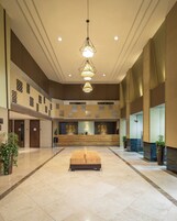 A spacious lobby with a reception desk, a central seating area, and decorative wall patterns.