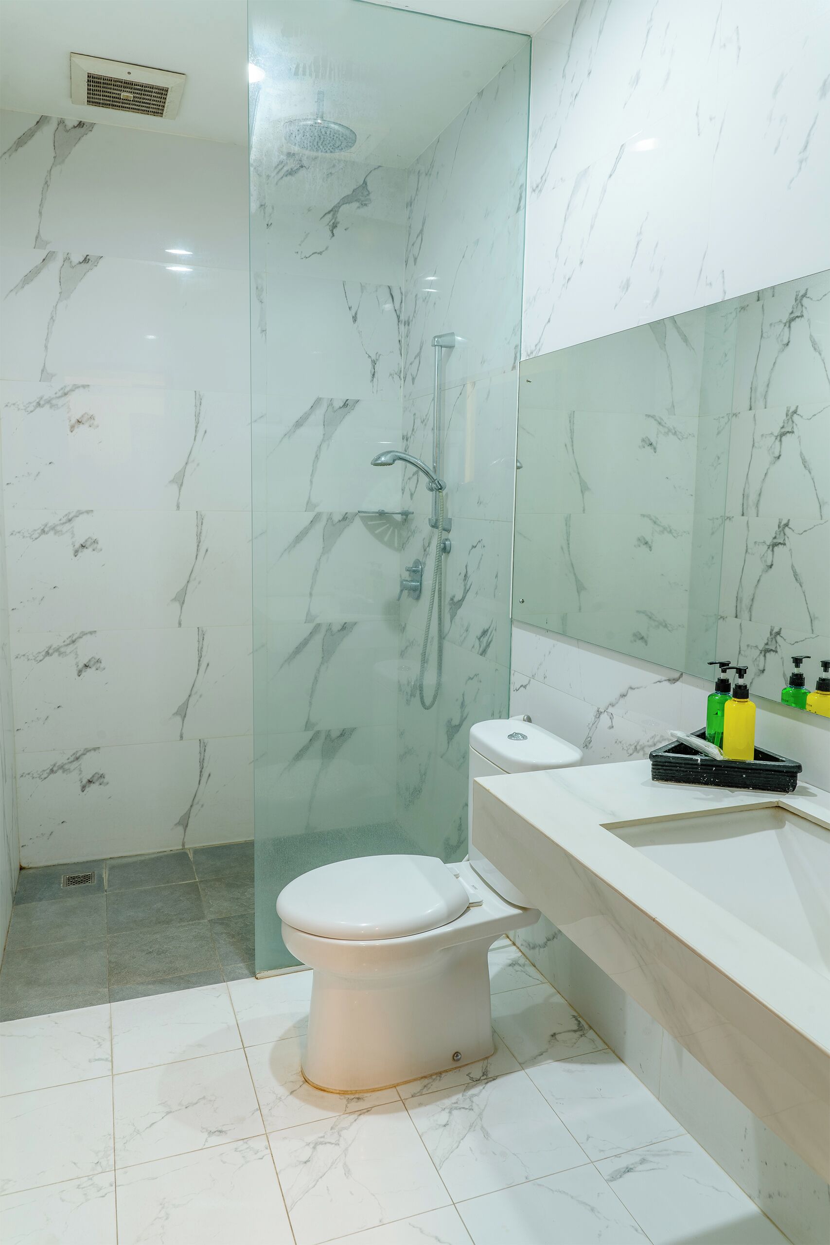 Une salle de bain avec une douche à parois de verre, des toilettes et un meuble-lavabo avec des articles de toilette.