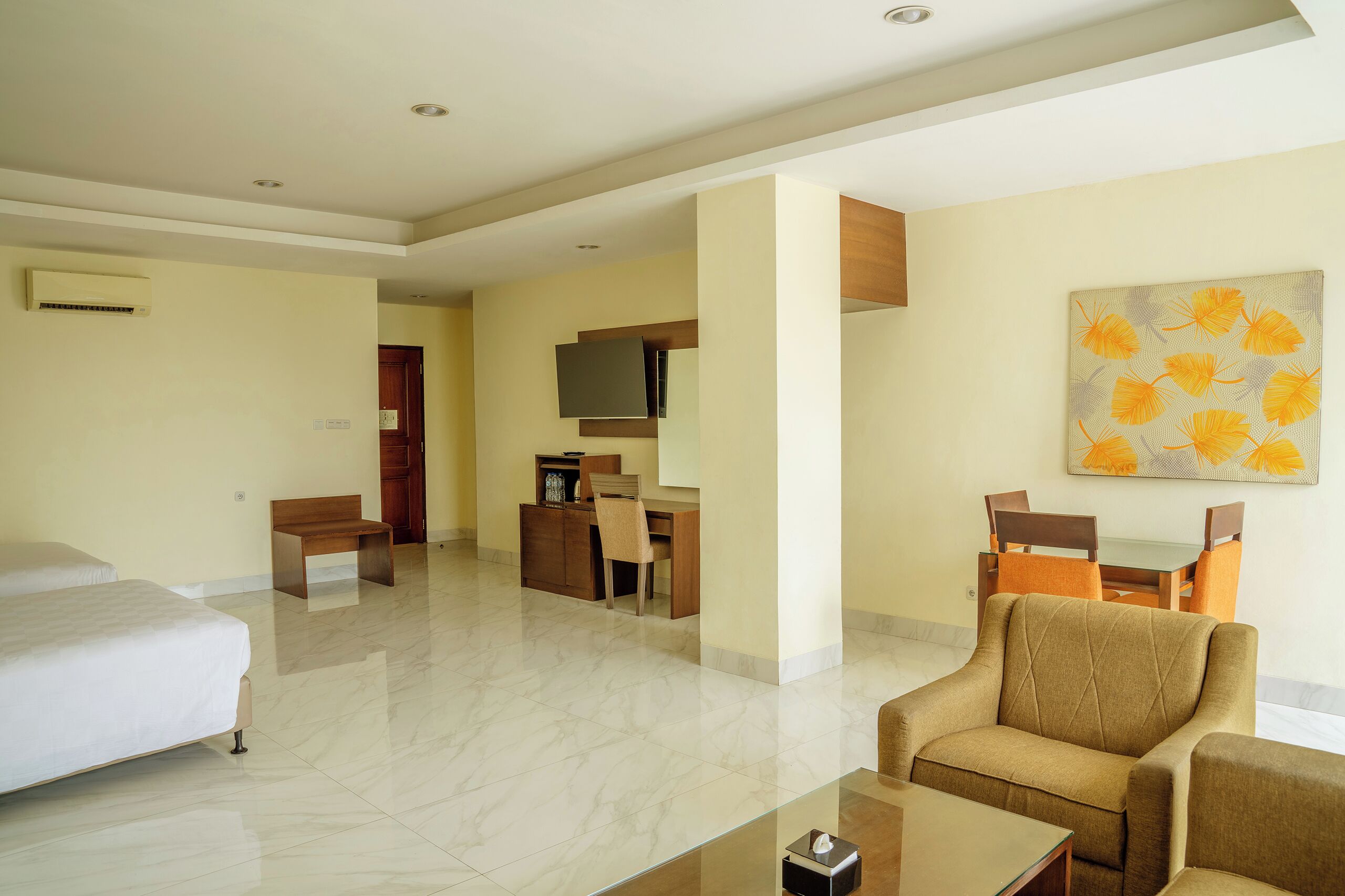 A hotel room with a bed, a desk, a chair, a sofa, and a dining table.
