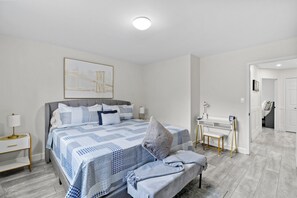 Ein modernes Schlafzimmer mit einem großen Bett, Nachttischen, einem Schreibtisch und einem Stuhl.