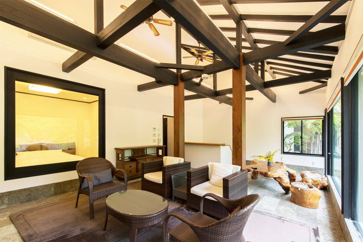 A modern interior with exposed wooden beams, wicker furniture, and a large mirror.