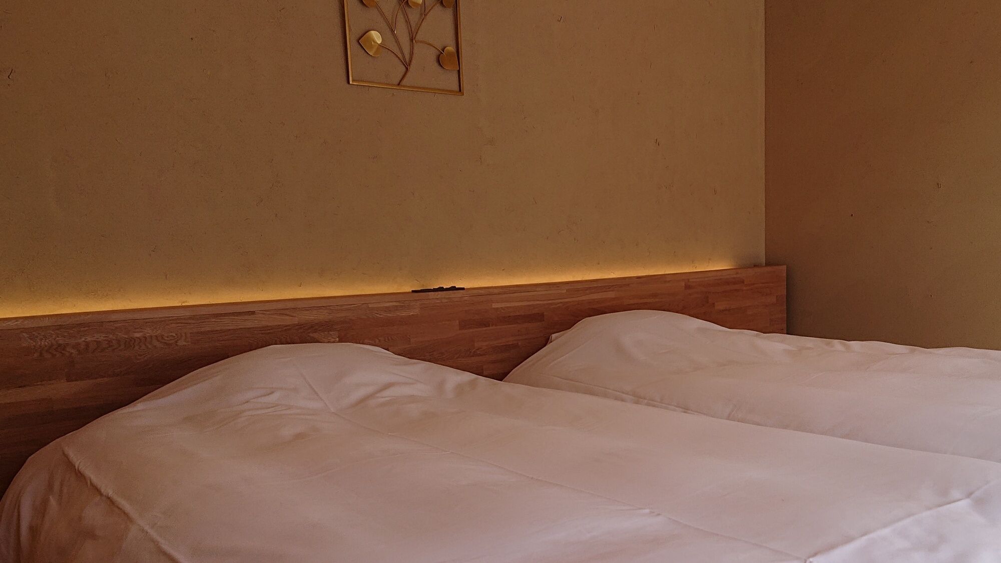 A hotel room with two beds, a wooden headboard, and a wall-mounted artwork.
