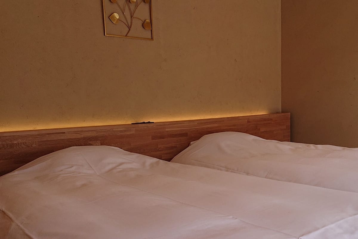 A hotel room with two beds, a wooden headboard, and a wall-mounted artwork.