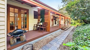 A house with a wooden deck, a barbecue grill, and a covered porch area. - Relax with your Best Friend in the heart of Tilba (Central Tilba)
