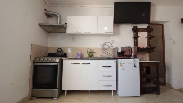 Een kleine keuken met een fornuis, oven, magnetron en een koelkast.