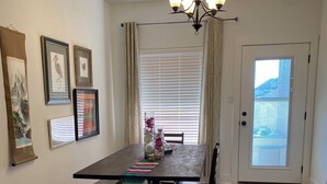 A dining area with a wooden table, dark chairs, a chandelier, framed artwork, and a view through a door. - Charming townhome.  3-bdrm, 2.5 bath with pool. 10 minutes to Kyle Field. (College Station)