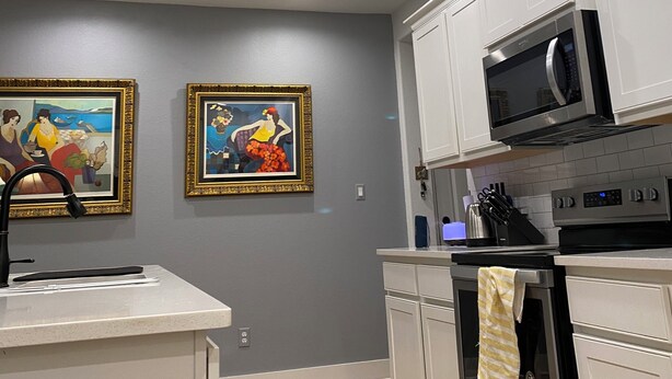 A modern kitchen with white cabinets, a stainless steel microwave, and an oven. There are two framed paintings on the wall. - Charming townhome.  3-bdrm, 2.5 bath with pool. 10 minutes to Kyle Field. (College Station)