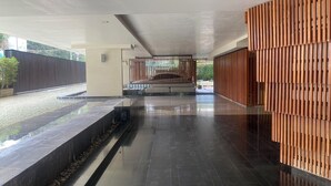 Eine großzügige Lobby mit modernem Design, mit spiegelndem Boden, einer Sitzgruppe mit Bänken und einer dekorativen Holzverkleidung.