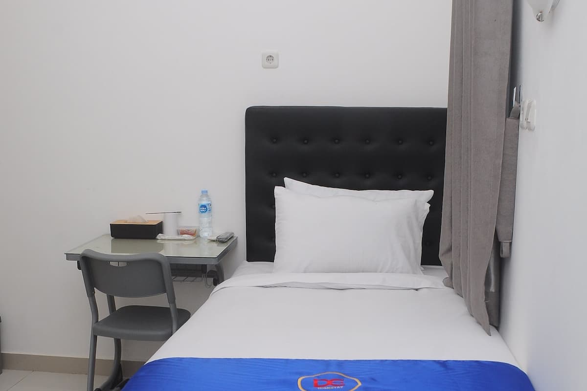 Een hotelkamer met een bed, een bureau, een stoel en een nachtkastje.