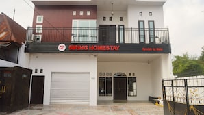 Ένα διώροφο κτίριο με μπαλκόνι, γκαράζ και μια πινακίδα που αναγράφει: «SIRING HOMESTAY».