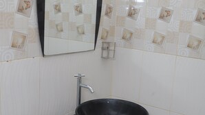 Ένα μπάνιο με έναν μαύρο νιπτήρα, έναν καθρέφτη και πλακάκια με σχέδια.