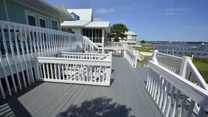 A wooden deck with white railings, leading to a house with a blue exterior and a white roof. - Book w/ Phone + Save 10%! Private Pool + Walk 2 Beach! (Gulf Shores)
