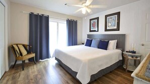 A bedroom with a large bed, a ceiling fan, a chair, a nightstand, and two framed pictures on the wall. - Book w/ Phone + Save 10%! Private Pool + Walk 2 Beach! (Gulf Shores)