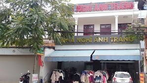A storefront with a sign reading "NHA NGHI ANH TRAO" and clothing items displayed outside. - Anh Trang Hostel LS - by BAY LUXURY (Tam Thanh)