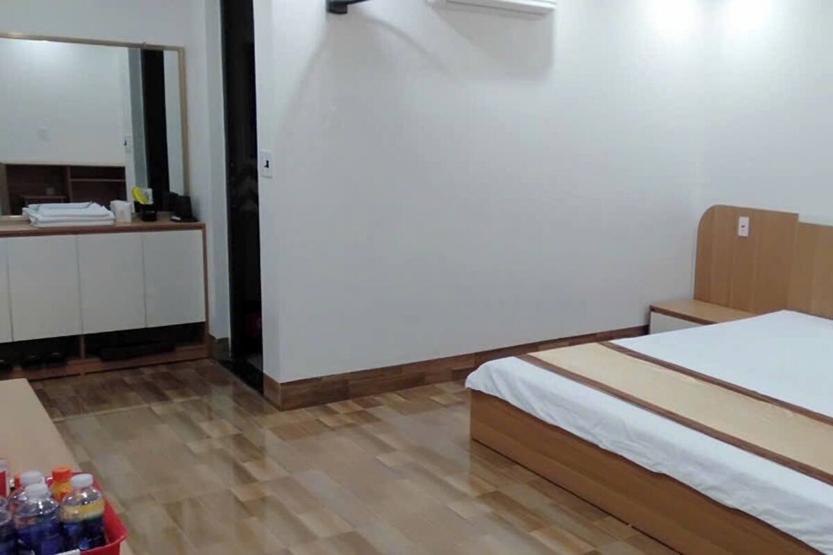 Een slaapkamer met een houten bed, witte beddengoed, een klein nachtkastje en een kledingkast.